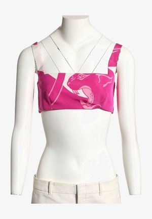 Top corto rosa con tirantes anchos que presenta un gráfico audaz de una cara de gato rugiente sobre un torso de maniquí blanco.