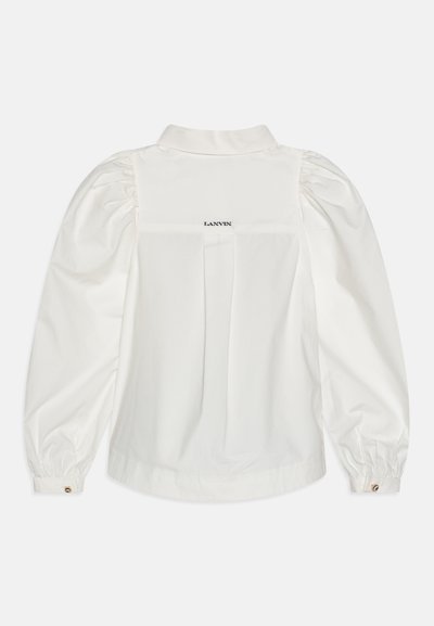 Vit bomullsblus med puffärmar, knappmanschetter och bakfåll. Har "LANVIN"-logotypen broderad på övre ryggen. Slät textur.