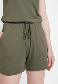 Olivgröna shorts i bomullsblandning med elastisk midja, justerbar dragsko och sidfickor, med en mjuk och slät textur.