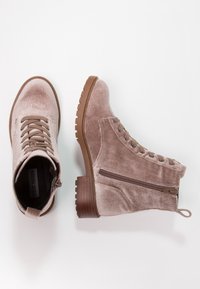 Une paire de bottines en velours marron clair à lacets avec fermeture éclair sur le côté et un gros talon en bois sur fond blanc.