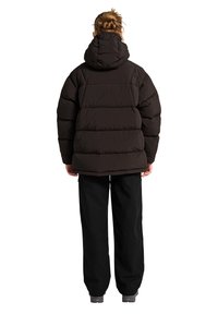Sort dunjakke med hætte, med en quiltet design og løst fit, parret med sorte vide bukser.