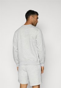 Gray sweatshirt with a round neck, ribbed cuffs, and hem, paired with matching gray shorts. Soft fabric with a smooth texture.