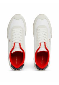 Białe sneakersy z gładką cholewką, czerwoną podszewką i teksturowanymi szarymi akcentami. Posiadają sznurówki i małe logo z boku.