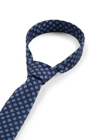 Cravate bleu marine en tissu texturé avec un motif de pois bleu clair, nouée au cou, formant une forme de boucle.