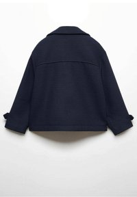 Mörkblå vävd jacka med krage, nedhasade axlar och uppvikta ärmar. Har en ryggsöm och rak fåll.