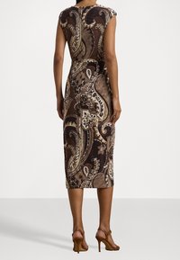 Braunes Paisley-Midi-Kleid mit taillierter Passform, kurzen Ärmeln und komplizierten Blumenmustern. Getragen mit braunen Absatzsandalen.