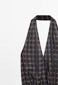 Black and blue plaid halter top with metallic gold stripes. Features a deep V-neck design and smooth, lightweight fabric.