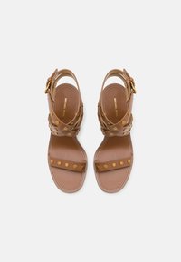 Brune lær sandaler med naglede stropper, åben bag og flad sål. Hardware i guldtonet på ankelstroppen.