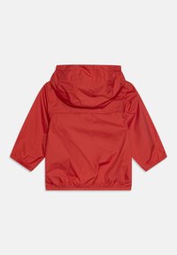 Raudona lengva striukė su kapisonu, elastingomis rankogalvėmis ir surinktu apatine dalimi. Lygus, vandeniui atsparus audinys su paprastu dizainu. Atgalinis vaizdas.