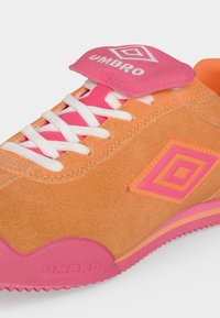Πορτοκαλί και ροζ παπούτσι από σουέντ με λευκά κορδόνια, λογότυπο Umbro στη γλώσσα και πλαϊνή πλευρά, με ροζ υφασμένη λαστιχένια σόλα.