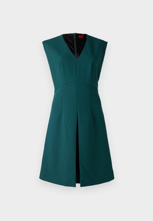 Zelené bezrukávové šaty s hlbokým výstrihom do V, štruktúrovaným dizajnom, predným rozparkom a kontrastnou čiernou podšívkou. Zapínanie na zips na chrbte.