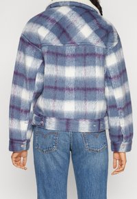Blå och vit rutig jacka med lila detaljer, med krage, långa ärmar och tryckknappar i nederkant, tillverkad i mjukt material.