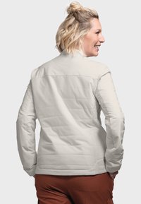 Light gray insulated jacket with a geometric quilted pattern. Features a high collar and long sleeves. Visible stitching and pockets.