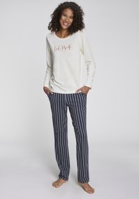 Långärmad krämfärgad topp med texten "LOVE", kombinerad med marinblå randiga byxor. Mjukt tyg; avslappnad passform; enkel design.
