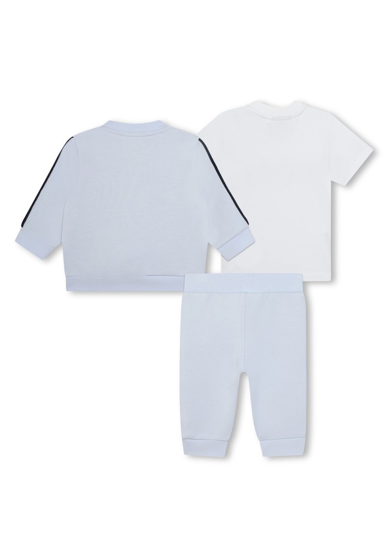 Chaqueta de chándal de algodón azul claro con una franja negra, combinada con una camiseta blanca y pantalones azul claro a juego con puños acanalados.