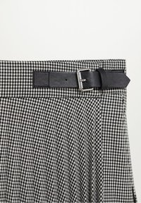 Jupe à carreaux vichy noir et blanc avec une taille dotée d'une ceinture en cuir noir et d'une boucle argentée, présentant une texture plissée.