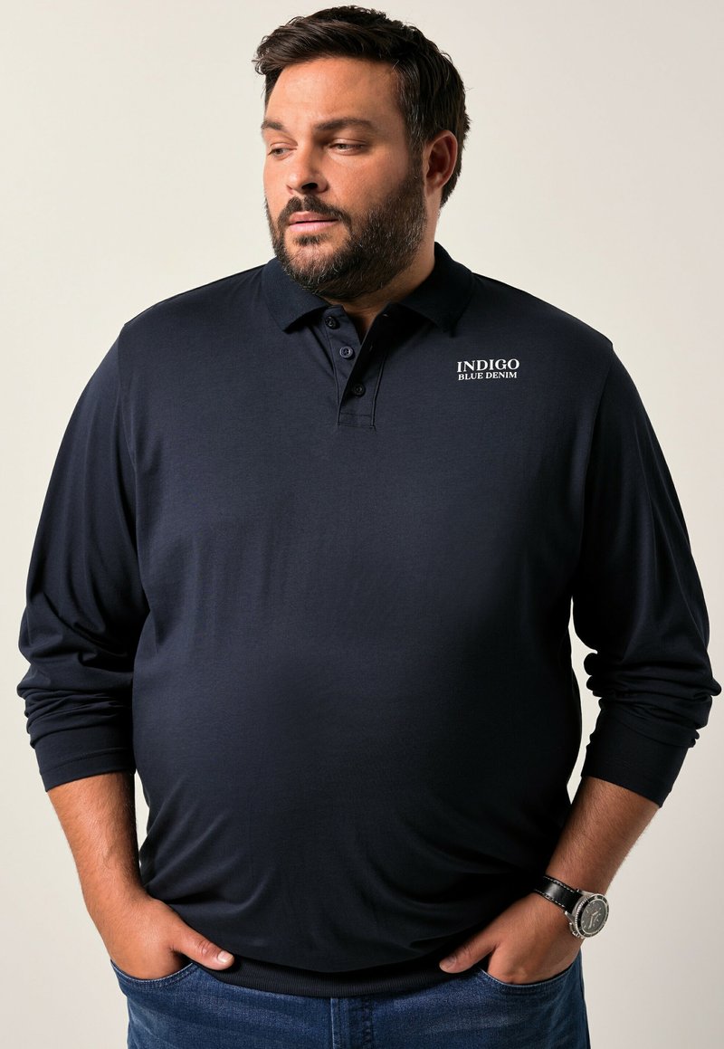 Námořnický polo trikota s dlouhým rukávem vyrobený z hladké látky, s límečkem na knoflíky a bílým logem "INDIGO BLUE DENIM" na hrudi.