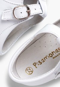 Witte leren schoenen met een ronde neus, een verstelbare band met een metalen gesp en een zachte binnenvoering met een reliëflogo.