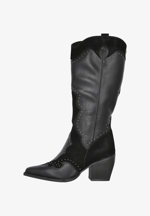 Botas de vaquero de cuero negro con un panel de ante negro texturizado, diseño único con bordes ondulados, adornadas con tachuelas plateadas y tacón cuadrado.