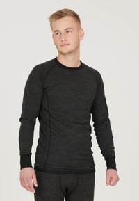 Langærmet termisk top i mørkegrå med struktureret strik, kontrasterende sort kant og tætsiddende design med raglanærmer.