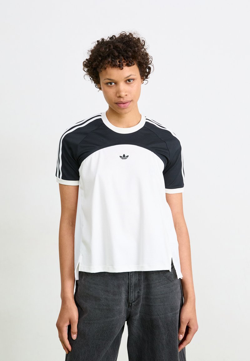 Balta ir juoda trumpų rankovių marškinėliai su apvaliu kaklu, su juodu kreiviu dizainu priekyje ir Adidas logotipu centrinėje krūtinės dalyje.