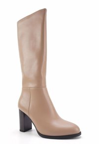 Beige Lederstiefel mit einer glatten Oberfläche, Blockabsatz, abgerundeter Zehenform und minimalen Nähten. Die Sohle hat eine schwarze Kante.