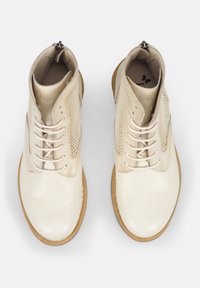 Botas de tobillo de cuero beige claro con una textura suave, que cuentan con paneles laterales de malla, cierre con cordones y suela de goma. Incluyen una cremallera lateral.