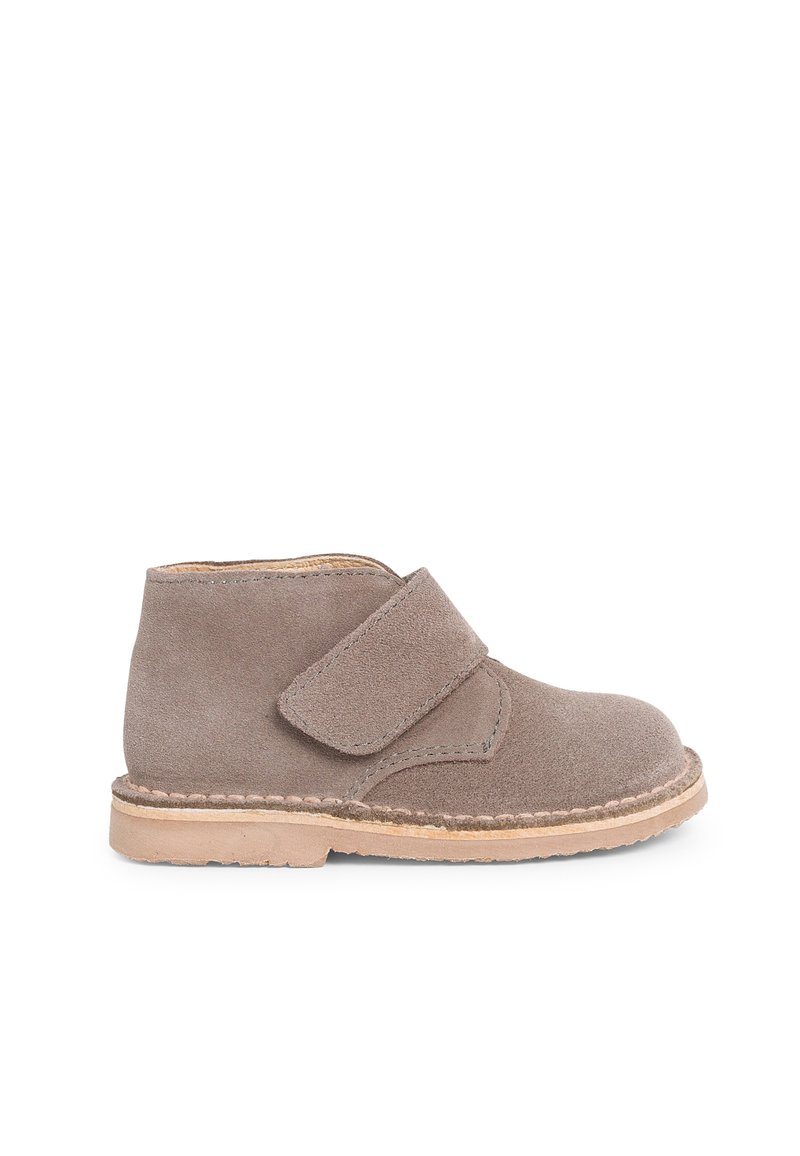 Stivaletti alla caviglia in suede grigio con una larga fascia in velcro e suola in gomma naturale, caratterizzati da dettagli cuciti lungo il bordo della suola.