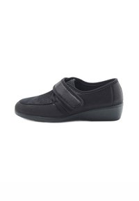 Scarpe slip-on nere con tomaia in tessuto testurizzato, cinturino regolabile in velcro e tacco basso per maggiore stabilità.