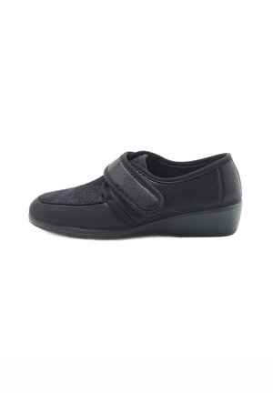Scarpe slip-on nere con tomaia in tessuto testurizzato, cinturino regolabile in velcro e tacco basso per maggiore stabilità.