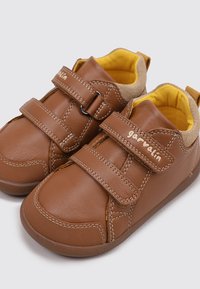 Chaussures en cuir marron avec doubles bandes Velcro, doublure intérieure jaune, design à bout rond, et détails de couture subtils.