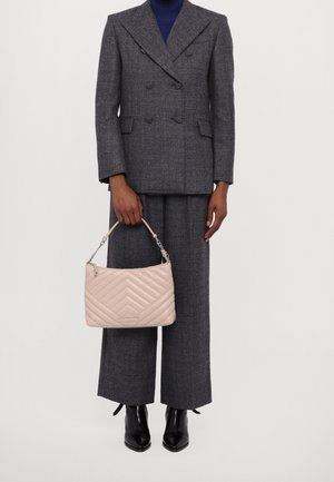 Beige quiltet læderhåndtaske med kæde og læderhåndtag, sammen med en grå dobbeltradet blazer og grå viddebukser.