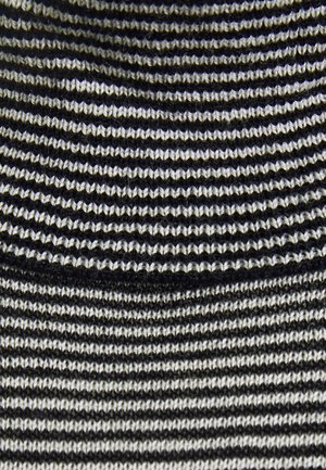 Lähikuva mustavalkoraidallisesta neuloksesta, jossa on vuorottelevia paksuja ja ohuita vaakasuoria nauhoja.