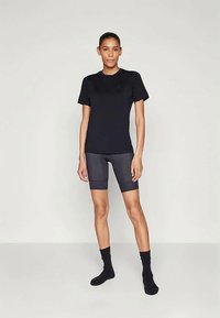 T-shirt preto de manga curta combinado com calções de bicicleta cinza escuro. Apresenta um design ajustado, textura suave e meias pretas até ao tornozelo.