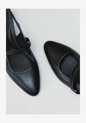 Czarne skórzane buty z ostrym noskiem i wycięciem w kształcie łuku. Posiada cienkie paski w okolicy kostki oraz gładką teksturę. Elegancki design, minimalistyczny styl.