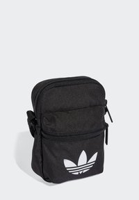 Borsa a tracolla nera in tessuto con due scomparti con zip e logo trefoil bianco di Adidas sul davanti. Forma compatta e rettangolare.
