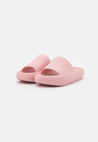 Sandales en caoutchouc rose avec un dessus texturé, orteils ouverts et une semelle épaisse et légère. Présente un design minimaliste et une finition lisse.