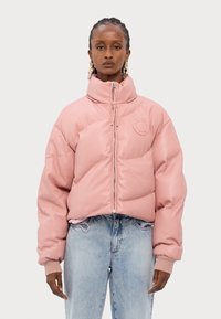 Rosa puffjacka med hög krage, dragkedja och logotypapplikation. Har ribbade manschetter och en kortad passform, i kombination med ljusblå jeans.