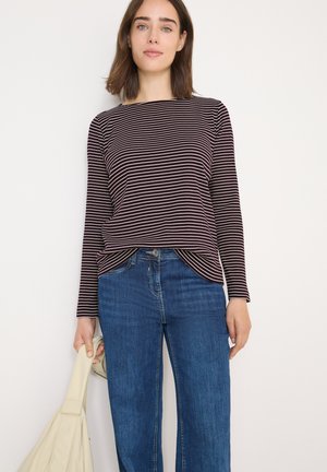 Gestreepte longsleeve top in donkerburgundy en wit; lichtgewicht stof met een ronde halslijn. Gepaard met blauwe rechte jeans en een beige tas.