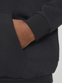 Black pullover hoodie with ribbed cuffs and a kangaroo pocket. Soft texture and minimal stitching details visible on the fabric.