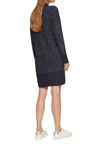 Vestido de punto navy con mangas largas, dobladillo acanalado y un corte relajado, combinado con zapatillas blancas que tienen acentos plateados en la parte trasera.