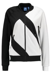 Black and white Adidas zip-up jacket with geometric diagonal stripes, mesh texture on white areas, and zippered side pockets.