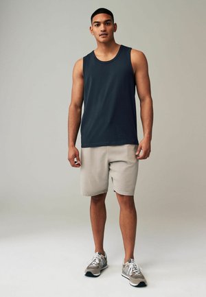 Mannen navy tanktop, beige shorts, grijze sportschoenen. Eenvoudig ontwerp met een ronde hals en lichtgewicht stof. Minimalistische esthetiek.