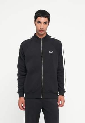 Black zip-up sweatshirt with a high collar, white stripes along the sleeves, and a small "GAP" logo on the chest. Baumwolle blend fabric.