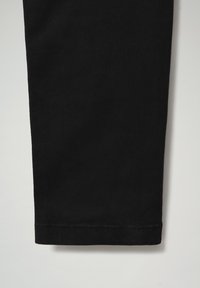 Zwarte tapperde broek met een gladde stoftextuur en een rechte zoom. Kenmerkt zich door stiksels langs de onderrand voor extra detail.