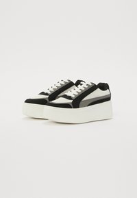 Baskets de plateforme noires et blanches en mesh et en suede, à bout rond, fermeture à lacets et semelle blanche texturée.