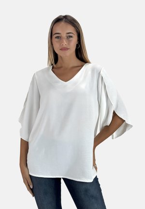 Blusa bianca con scollo a V, maniche corte e fluttuanti, morbida al tatto e dal taglio rilassato, abbinata a jeans in denim scuro. Design semplice, senza motivi.