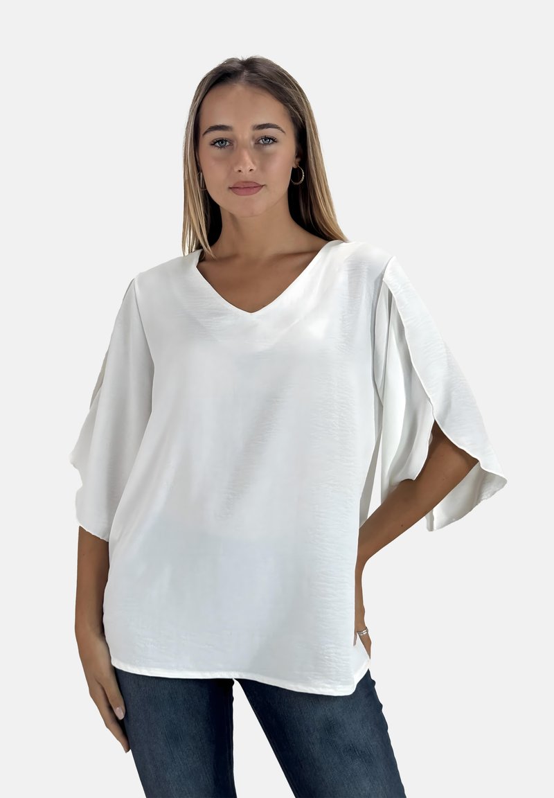 Witte V-hals blouse met korte, vloeiende mouwen, zachte textuur en een relaxte pasvorm, gecombineerd met donkere denim jeans. Eenvoudig ontwerp, geen patronen.