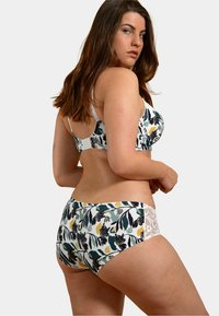 Ensemble de lingerie composé d'un soutien-gorge à imprimé floral et d'une culotte assortie en vert, blanc et jaune ; tissu doux avec des accents en dentelle sur la ceinture et les bretelles.