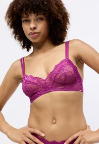 Čipkovaný bralet v živé fuchsiovej farbe s jemnými kvetinovými vzormi, nastaviteľné tenké ramienka a mäkký spodný pás pre pohodlie.